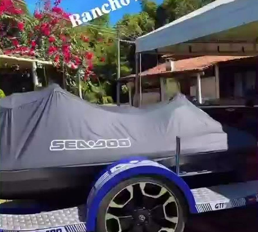 Jet ski Sea-Doo sobre a carreta, coberto, no gramado do rancho